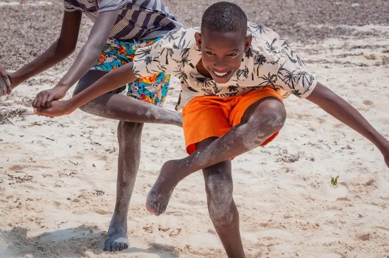 A boy standing on the beach doing yoga