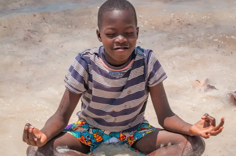 A boy doing yoga on the beach in Watamu Kenya