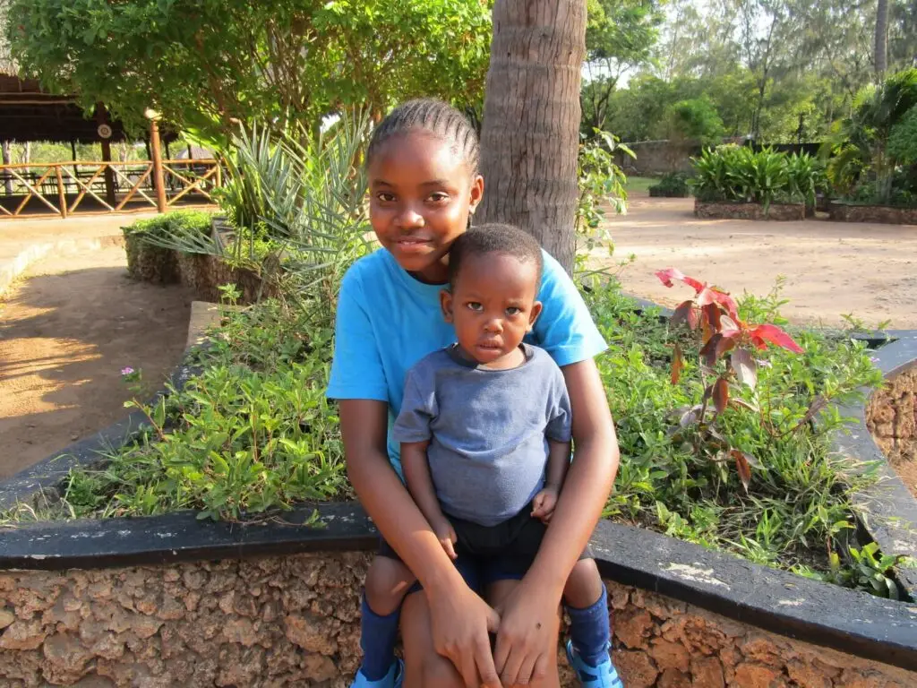 A girl with a small child at the Happy House children's home smiling