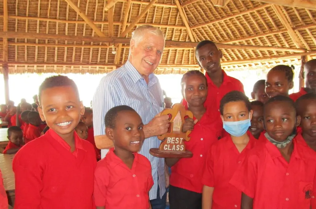 Papa Dave stood with a group of children holding up a best class award