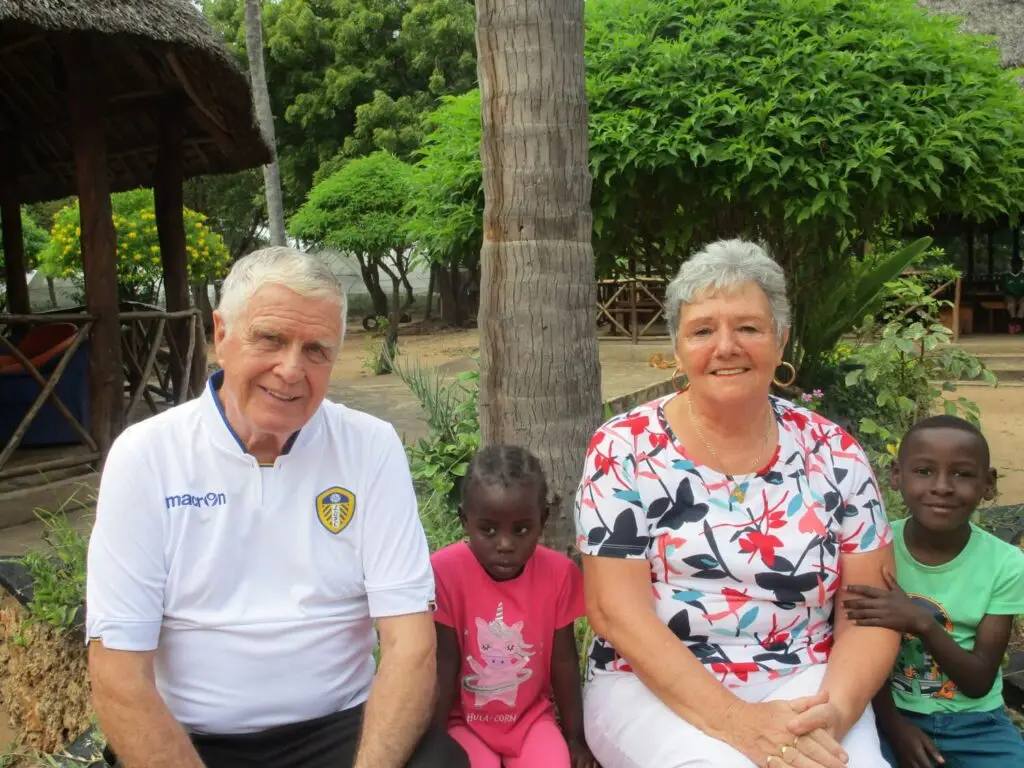 Papa Dave and Mama Sue are sat in the gardens with two children at the happy house smiling